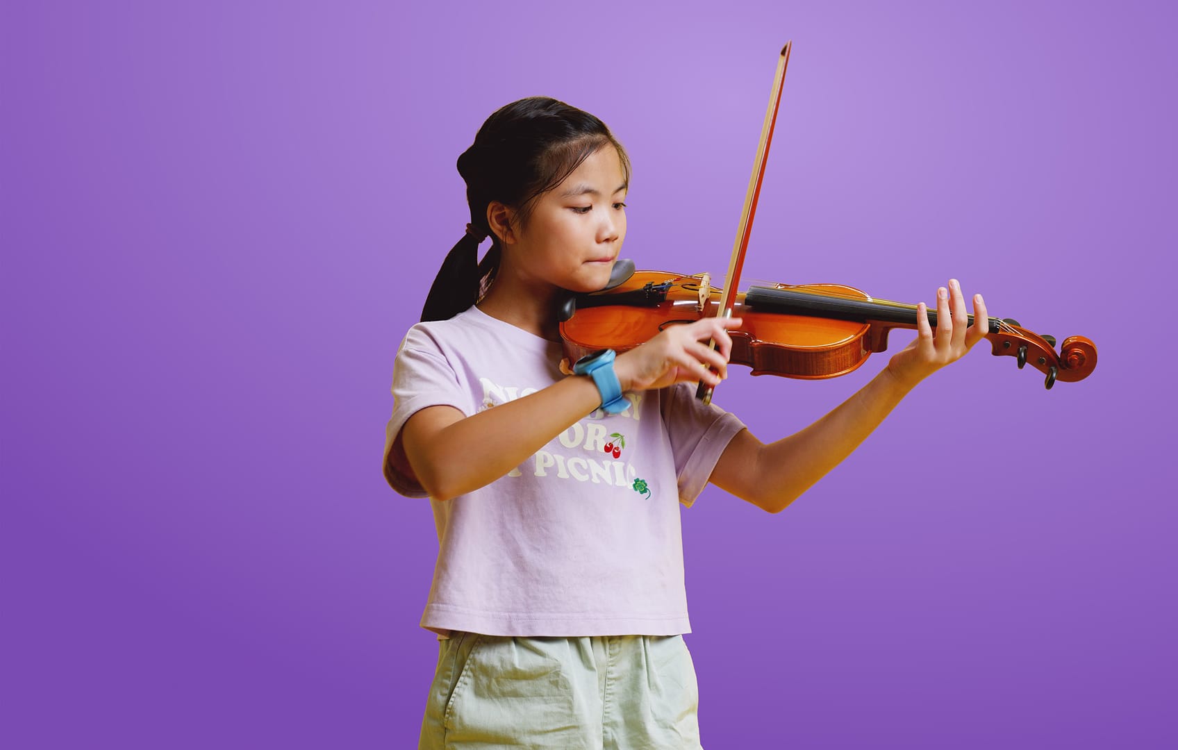 Menina tocando violino enquanto usa o Soundbrenner Spark