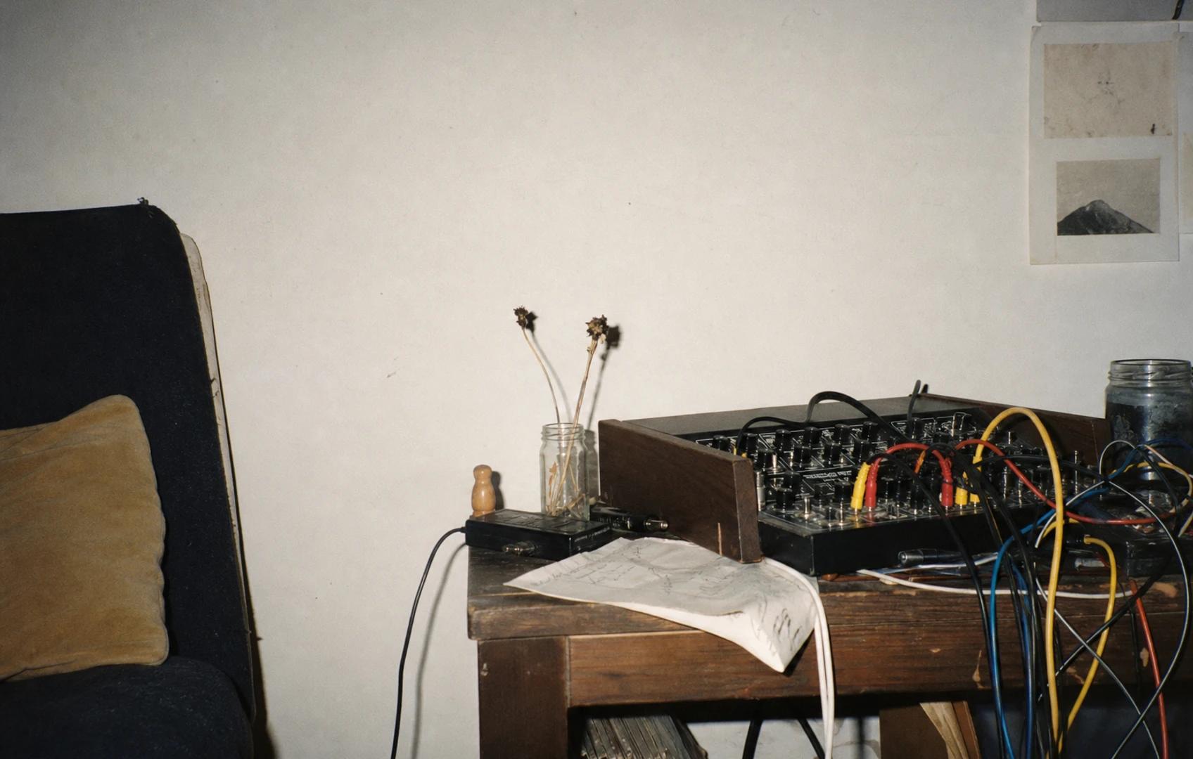 Hand-cut orange and cyan rhythm circles unravel into tangled waveform ribbons on a scuffed black paper field.