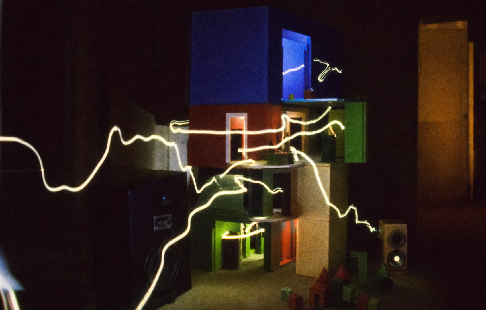 Bauhaus-style cut-paper rooms connected by a black waveform as small geometric player pieces move between them.