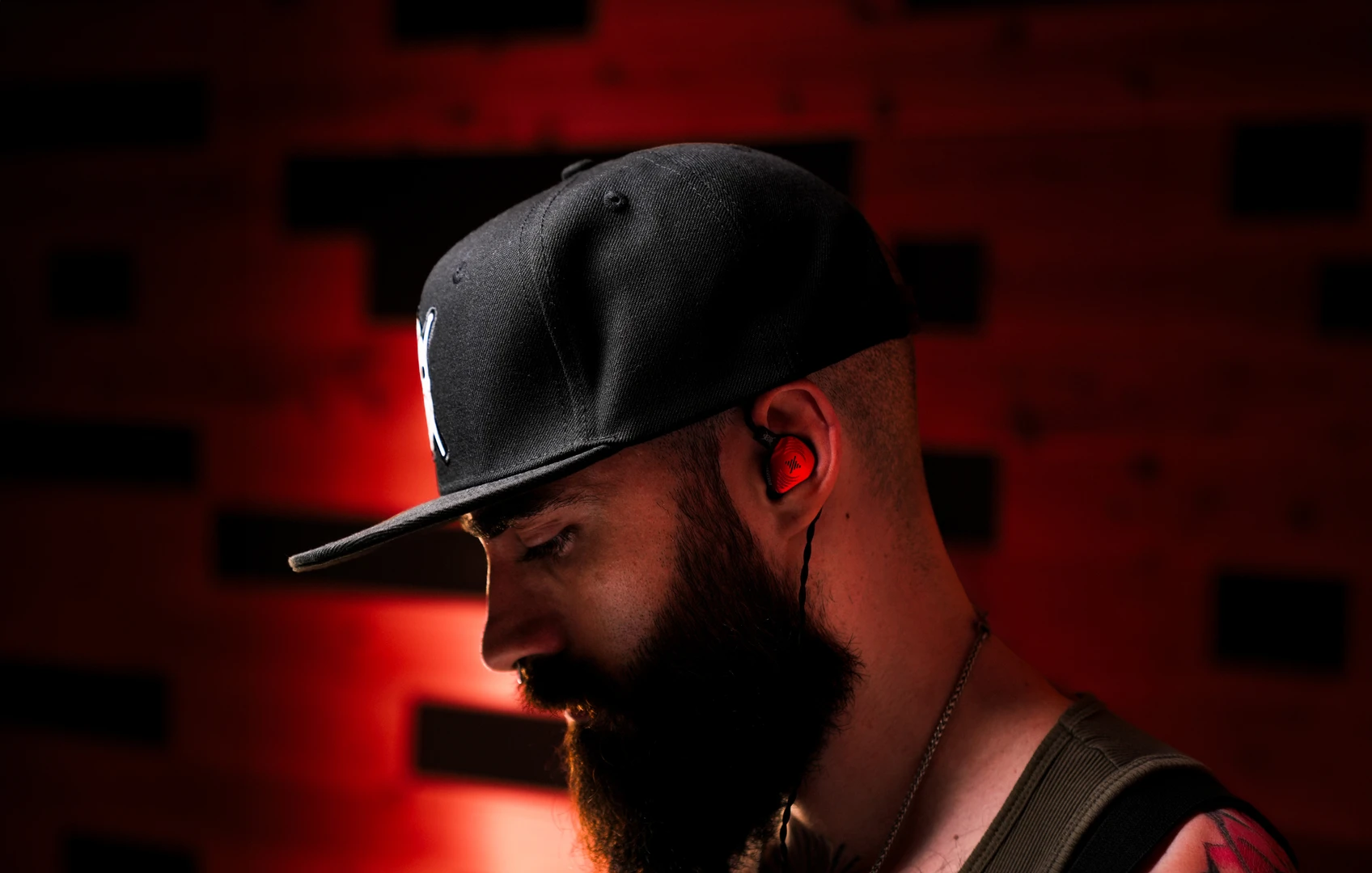 El Estepario Siberiano wearing the red Wave Pro 2 signature in-ear monitor in a red-lit studio