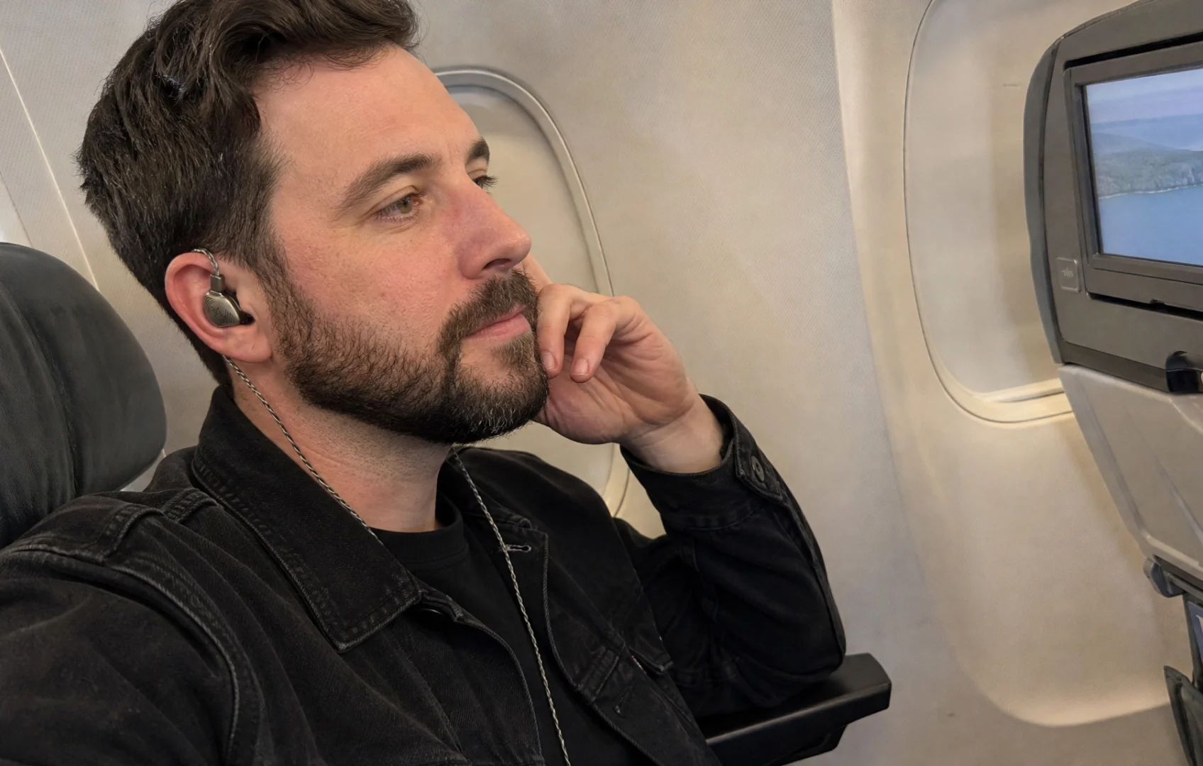 Traveler wearing wired in-ear monitors during a flight