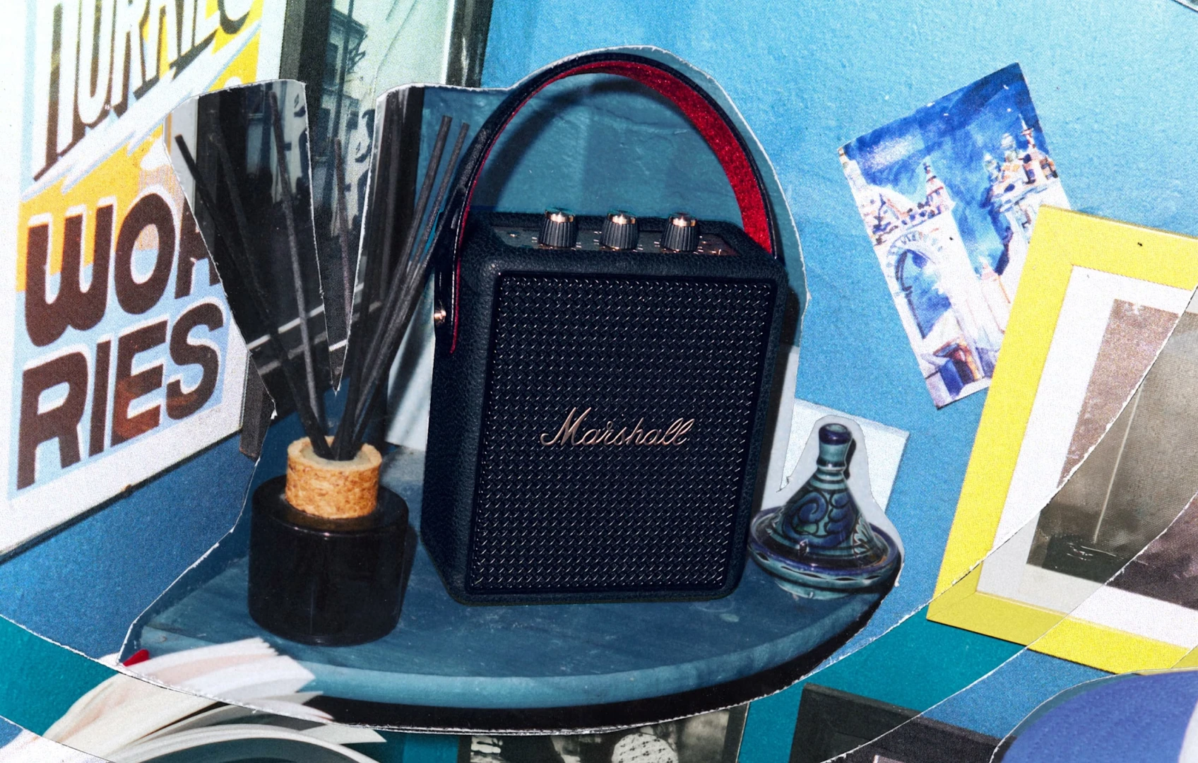 Marshall Stockwell III portable speaker on a blue table in a collage-style lifestyle scene with posters and small objects around it